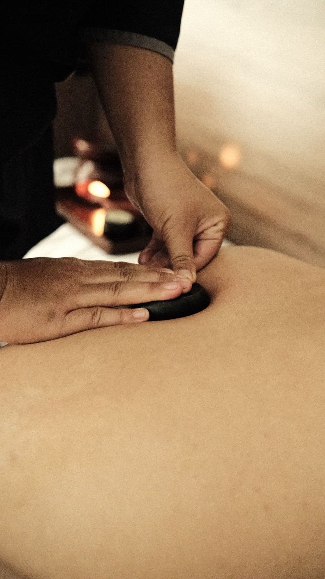 Batu basal hangat ditata di punggung saat sesi hot stone massage